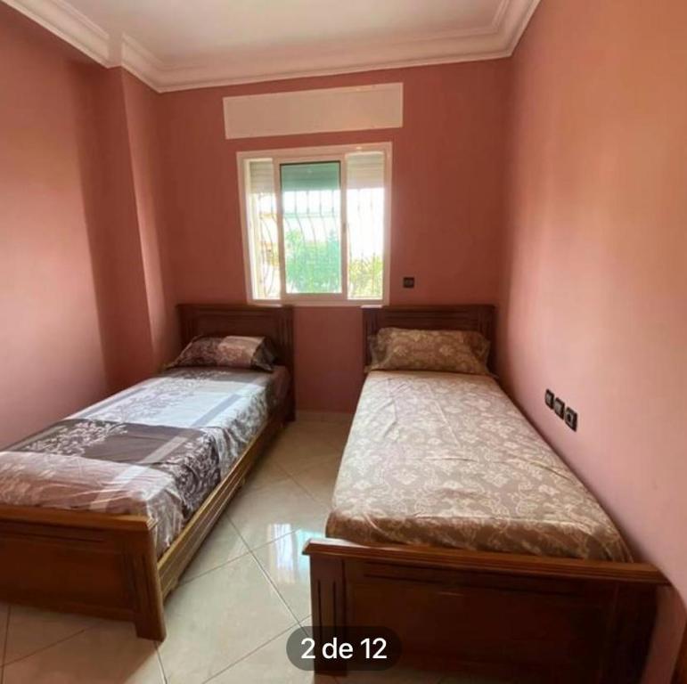 twee bedden in een kamer met een raam bij val fleuri résidences Tanger in Tanger