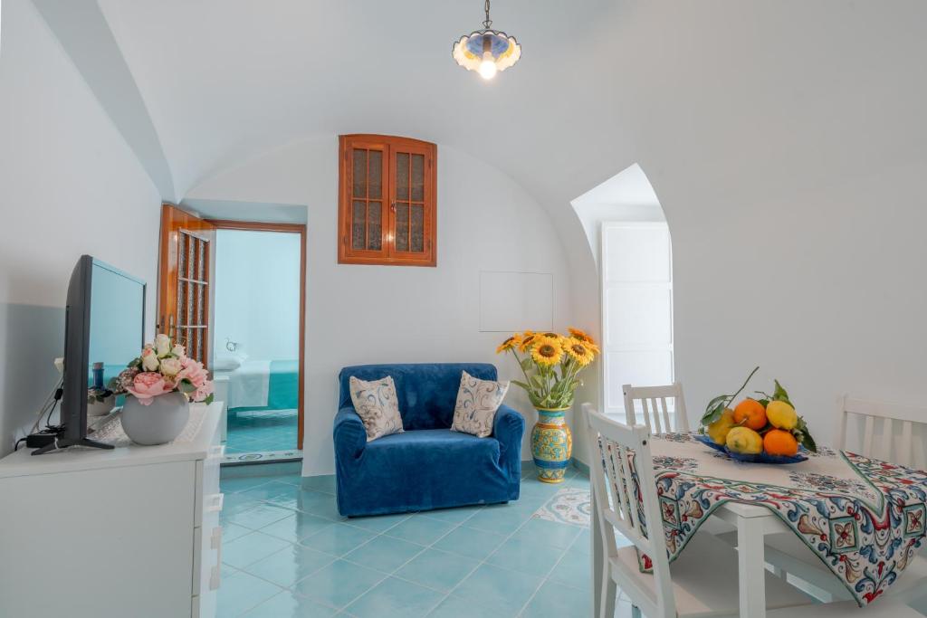 ein Wohnzimmer mit einem blauen Stuhl und einem TV in der Unterkunft Little House in Minori