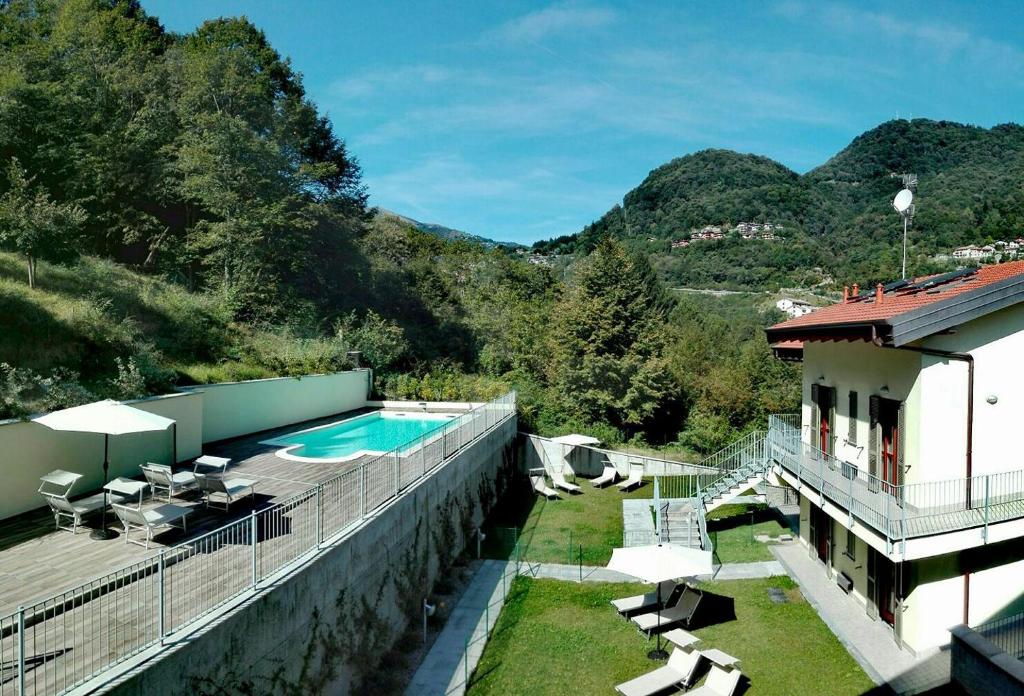 une maison avec une piscine et des montagnes en arrière-plan dans l'établissement Vista Dolce Isola _ Lakeview Pool, Terrace & Garden apartment, à Argegno
