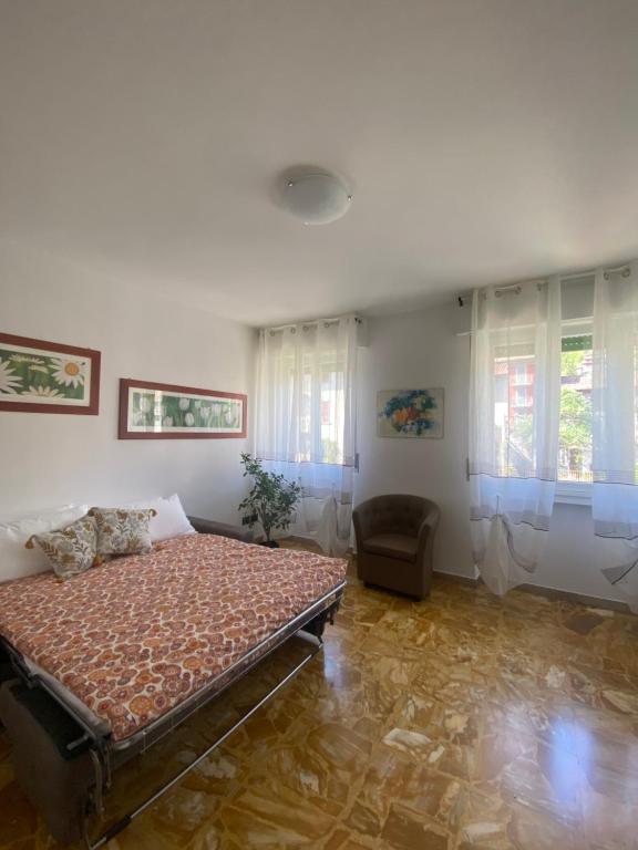 um quarto com uma cama, uma cadeira e janelas em Sole , Neve e Relax em Clusone