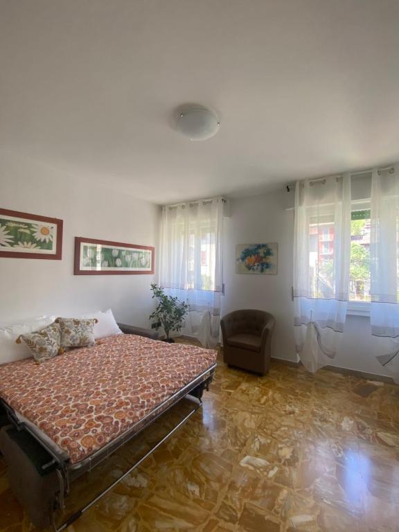 a bedroom with a bed and a chair and windows at Sole , Neve e Relax in Clusone
