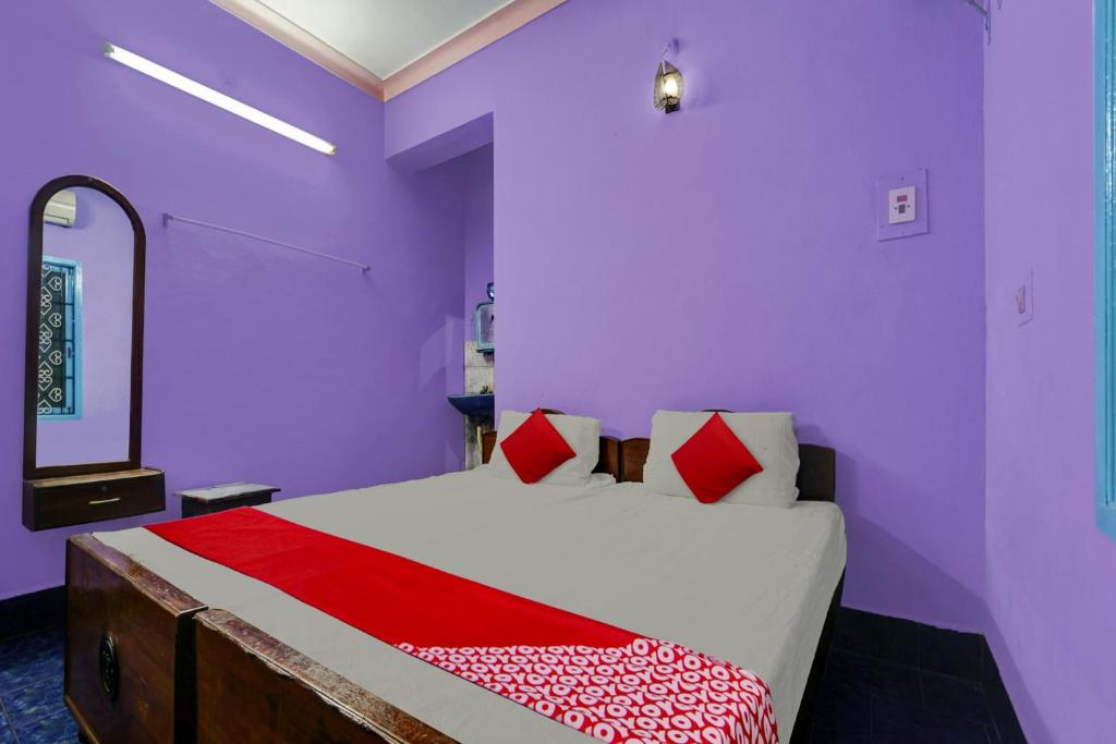 een paarse kamer met een bed en een spiegel bij OYO Sri Sivasakthi A/C Lodge in Sivakāsi