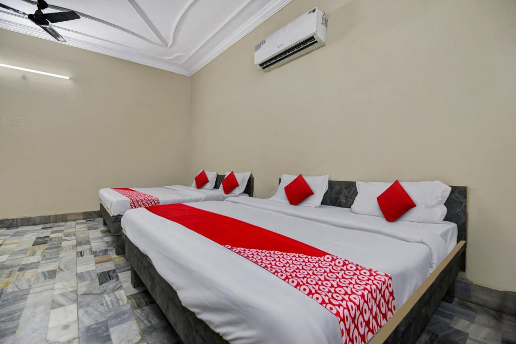 a bedroom with two beds with red and white pillows at OYO Hotel Real Residency in Jodhpur