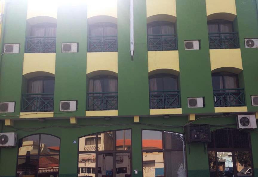 un edificio verde y blanco con ventanas en Felicidade Hotel en Praia