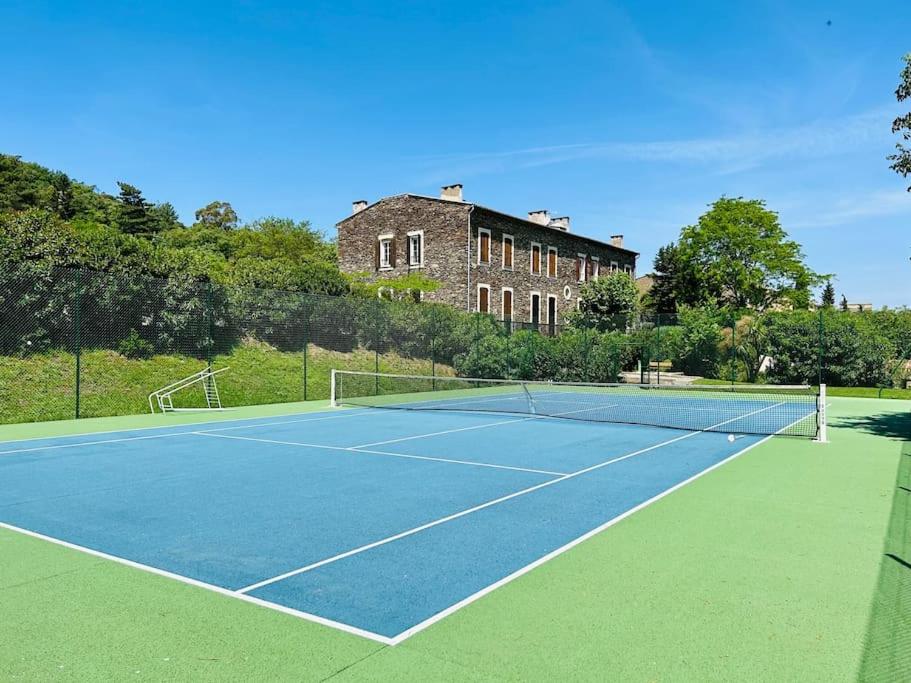 a tennis court with a building in the background at Studio avec piscine et tennis in La Garde-Freinet