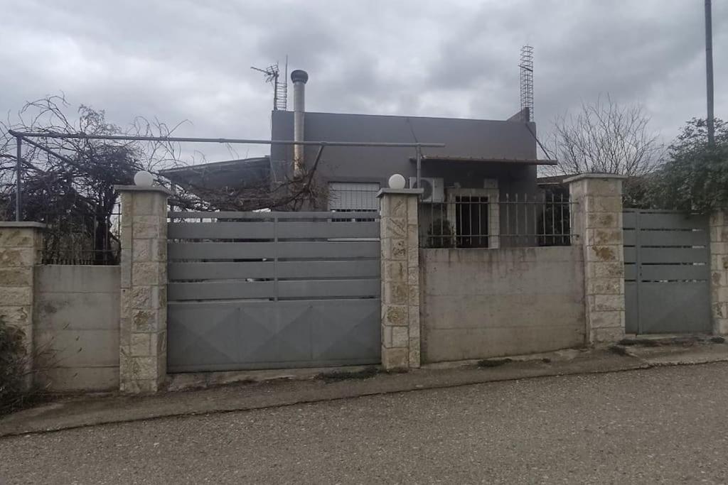 una cerca frente a una casa con una puerta en Βίλα στην Πάτρα, en Patra