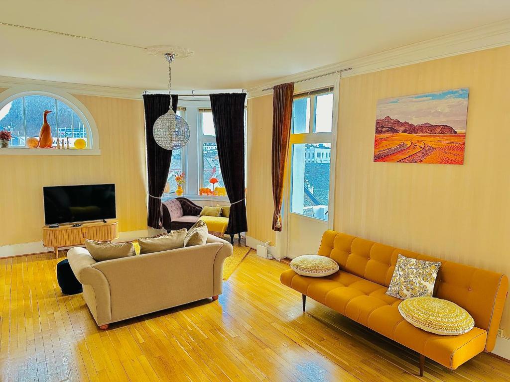 a living room with a couch and a tv at Stylish big Jugend art nouveau apartment with balcony heart of Alesund in Ålesund