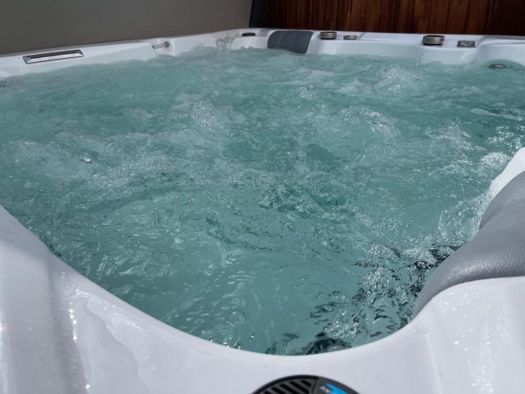 a bath tub filled with blue green water at Modernes Apartment mit Whirlpool & Gartensauna in Geisenheim