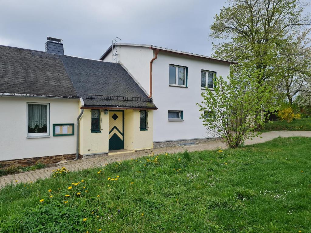 Biały dom z czarnym dachem i dziedzińcem w obiekcie Ferienwohnung Erzgebirgsblick w mieście Bernsbach