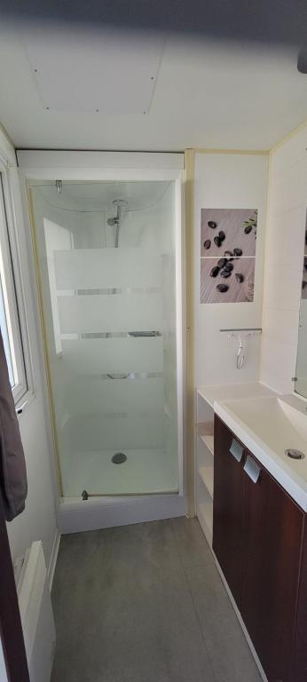 a bathroom with a glass shower and a sink at Mobilhome 6 personnes in Parentis-en-Born