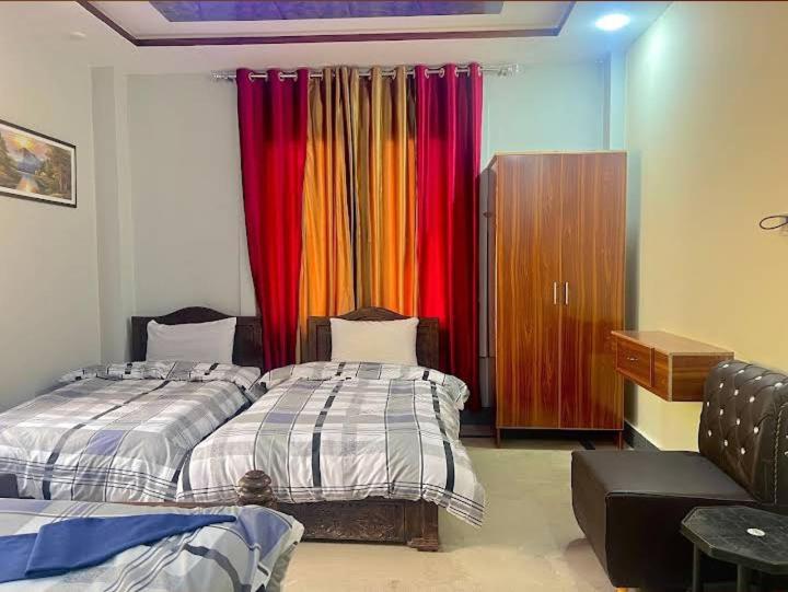 een slaapkamer met 2 bedden en kleurrijke gordijnen bij LeGrand Hotel & Resort in Swat