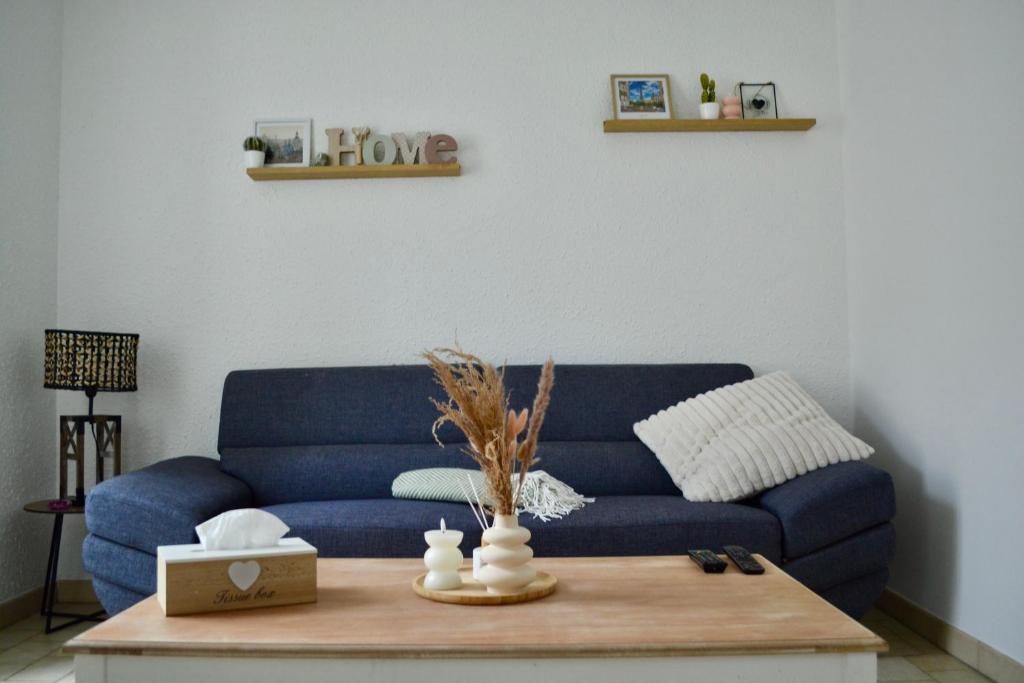 ein blaues Sofa im Wohnzimmer mit Couchtisch in der Unterkunft duplex nouvelle du gué in Pouilly-en-Auxois