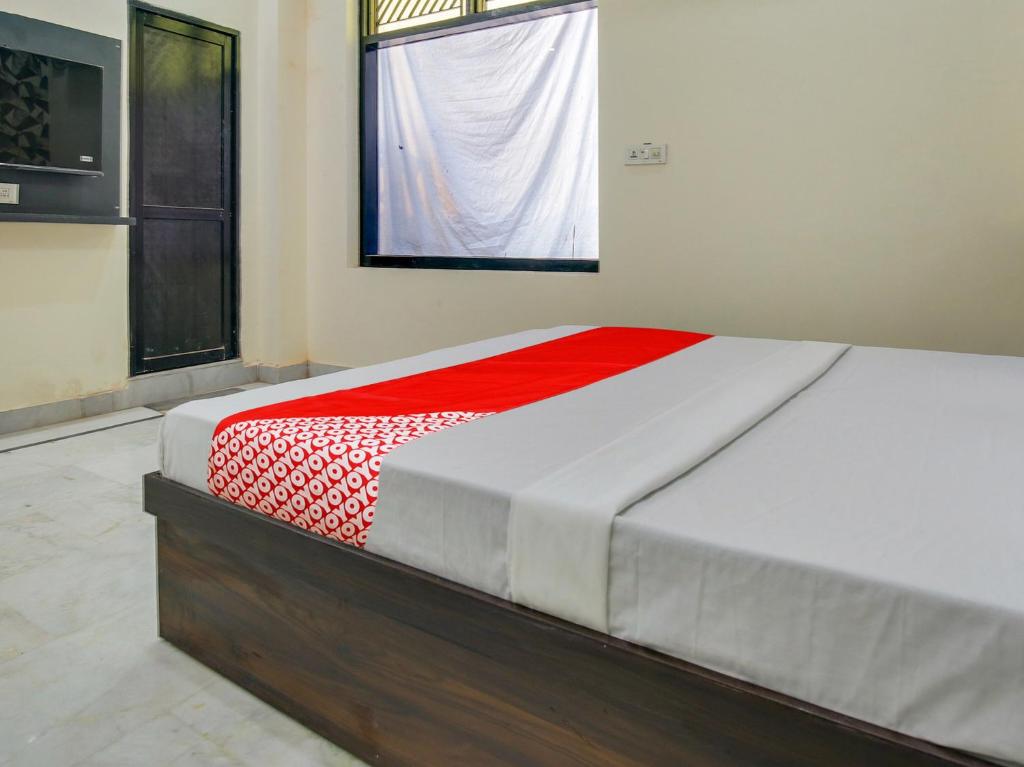 Cama en habitación con manta roja y blanca en Super OYO Hotel Orchid Regency en Ludhiana