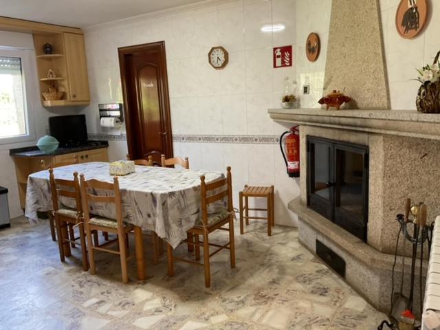 een eetkamer met een tafel en stoelen en een open haard bij A Casa do San Paio de Buscás in Ordes