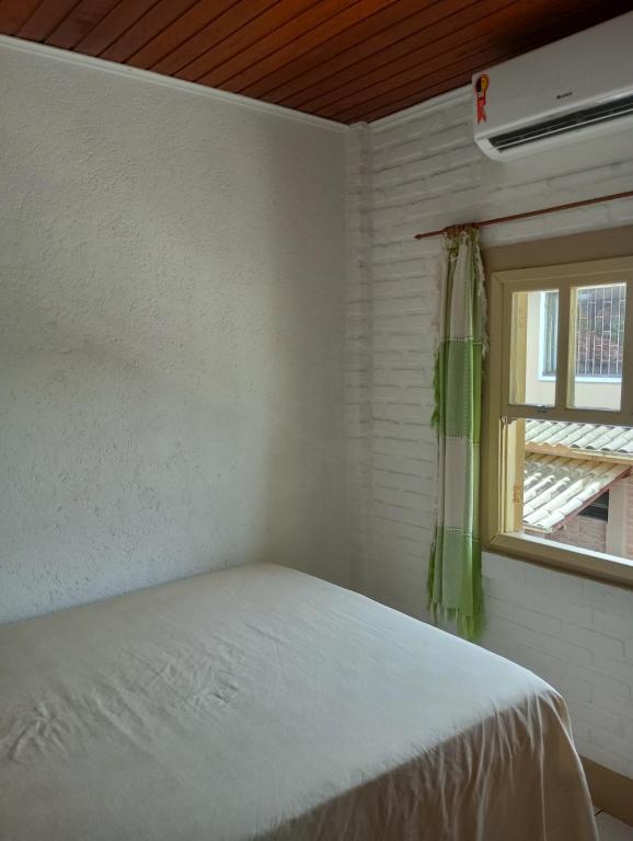 Habitación blanca con cama y ventana en Morada do Neu Ingleses, en Florianópolis
