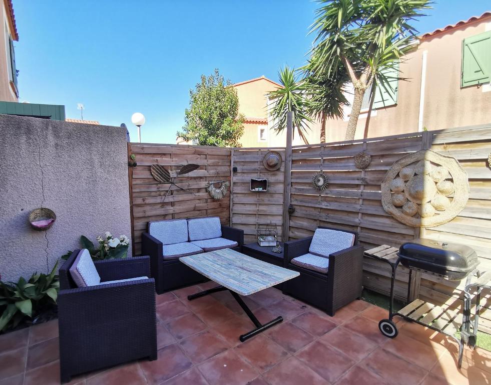 a patio with two chairs and a table and a grill at Petite maison cosy 4 couchages à 700 m de la plage in Torreilles