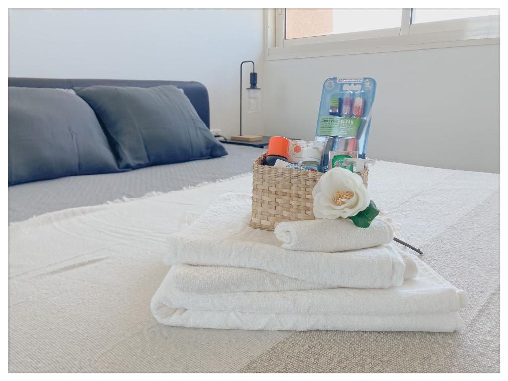 a pile of towels and a basket on a bed at Malaya suite in Caesarea