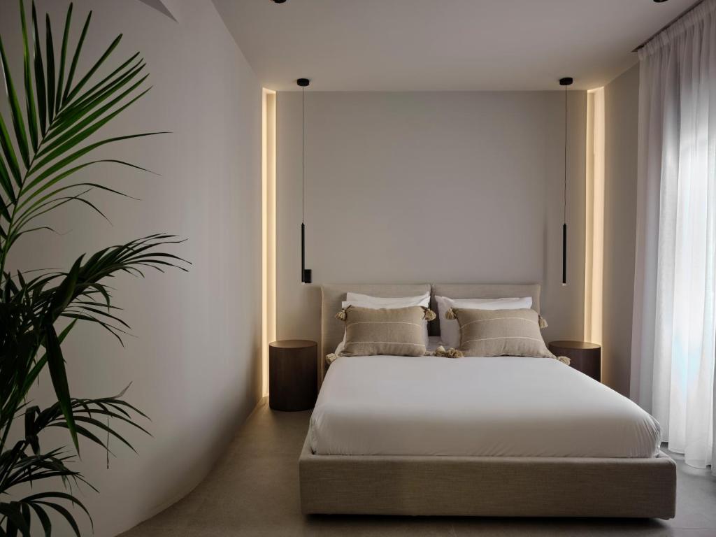 Un dormitorio con una cama blanca y una planta en Bond Smart Living Suites, en Atenas