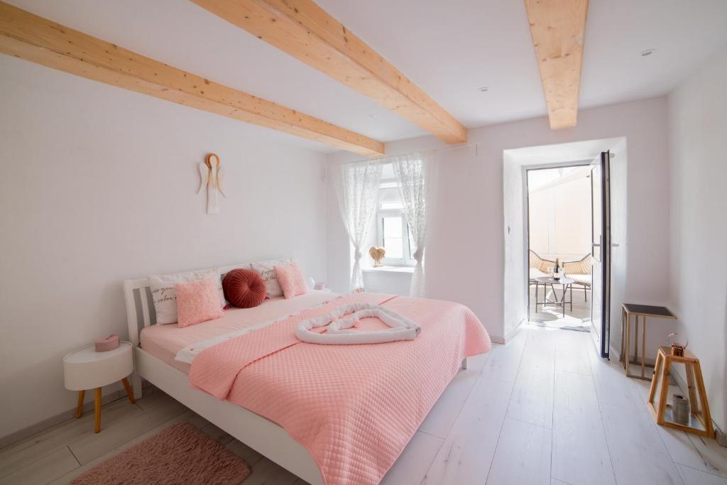 a white bedroom with a pink bed with a pink blanket at Lovely Stiavnica in Banská Štiavnica