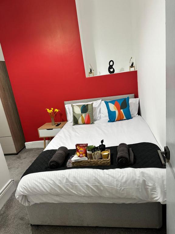 a bedroom with a bed with a red wall at Quirky Oasis Anfield in Liverpool