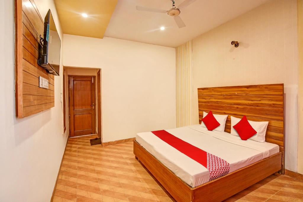 Super OYO Hotel NR Residency في Banūr: غرفة نوم بسرير ومخدات حمراء