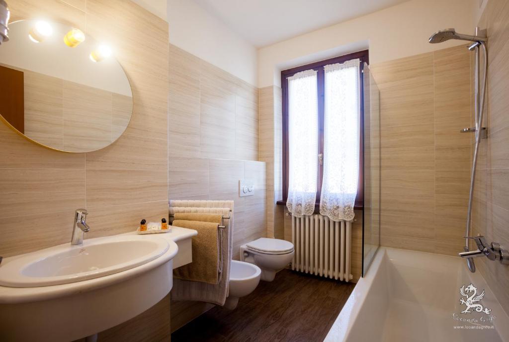 een badkamer met een wastafel, een toilet en een spiegel bij Il Grifo in Lenno