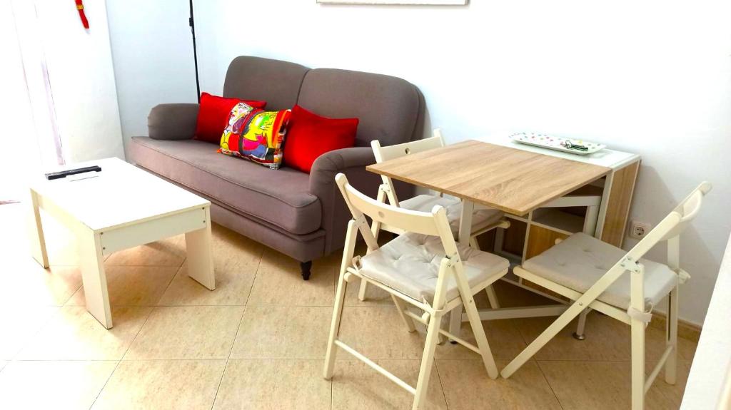 sala de estar con sofá, mesa y sillas en Sol Centro Apartment A, en Sevilla