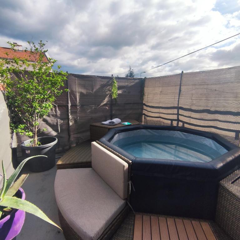 un bain à remous installé sur une terrasse avec une clôture dans l'établissement Maison de charme avec jacuzzi, à Saint-Étienne
