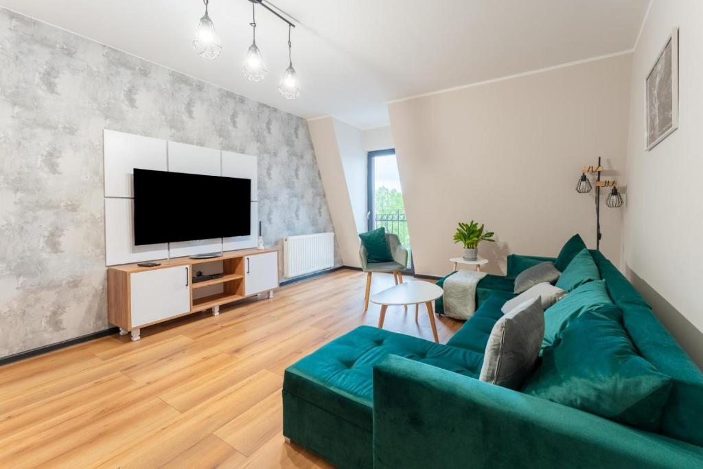 a living room with a green couch and a flat screen tv at Apartament przy Baszcie - z prywatnym parkingiem w centrum - by SpaceApart in Jelenia Góra