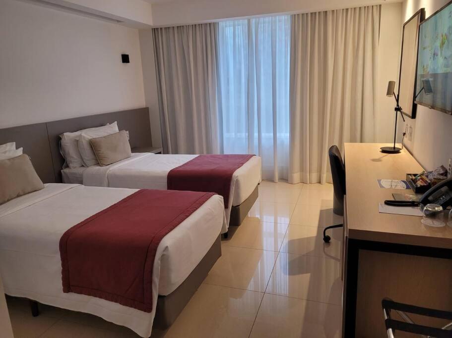 Una habitación de hotel con dos camas y un escritorio. en Alvorada Hotel - Eixo Monumental, en Brasilia