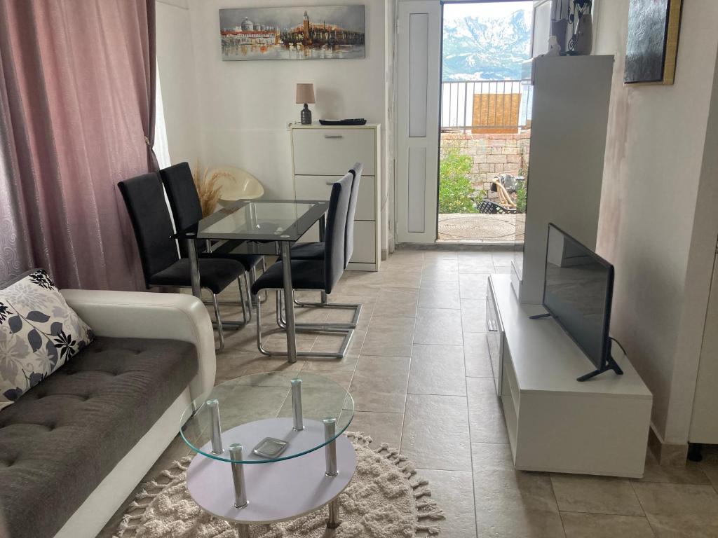 a living room with a couch and a table and a television at Plaža Stari Grad Budva pjena od mora Beach Apartman in Budva