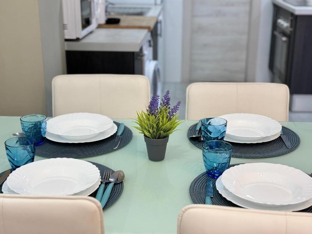 a table with plates and blue glasses on it at Apartamento Sofía I a 500m de la Playa con Parking solo para motos y bicicletas in Puerto de Sagunto