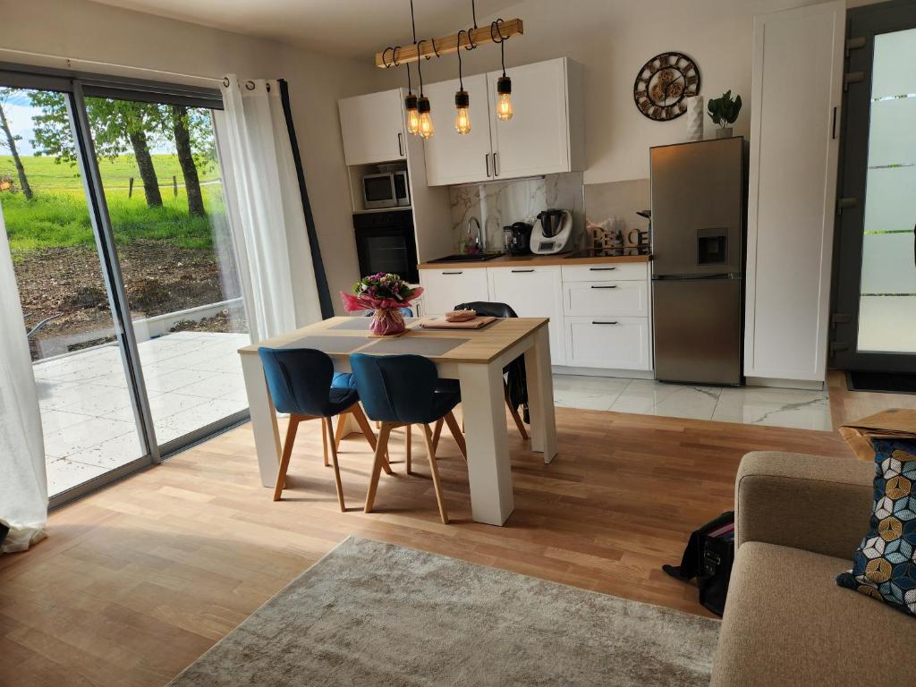 een keuken met een tafel en stoelen en een koelkast bij La petite maison d'Adèle 