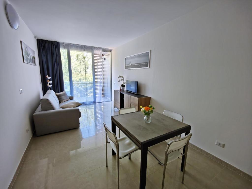 a living room with a table and chairs and a couch at Apartment Mare45 - 10 minutes walk from the beach - included parking, umbrella and sun-beds in Eraclea Mare