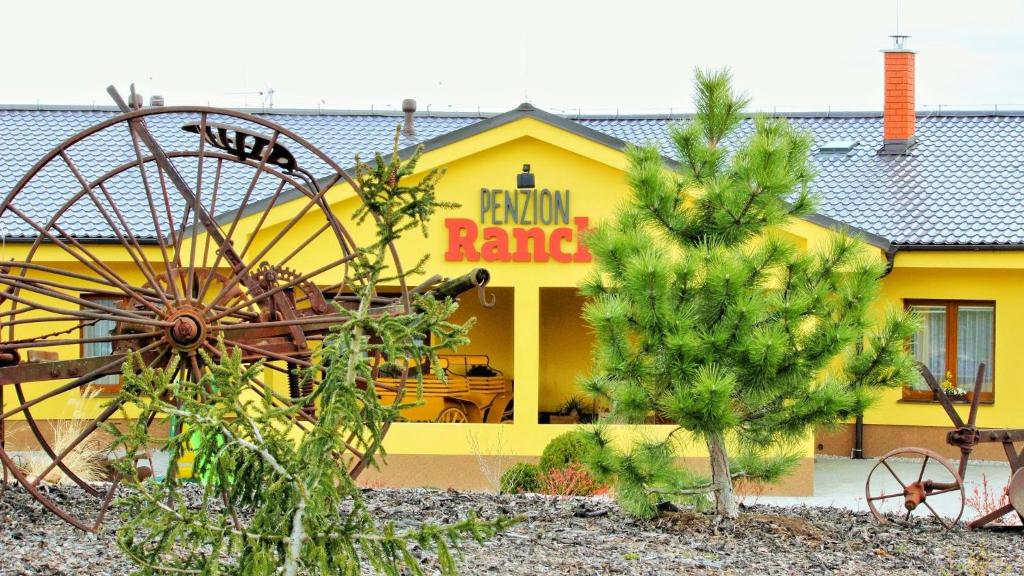 a yellow building with a wheel in front of it at Penzion Ranch in Hořovice