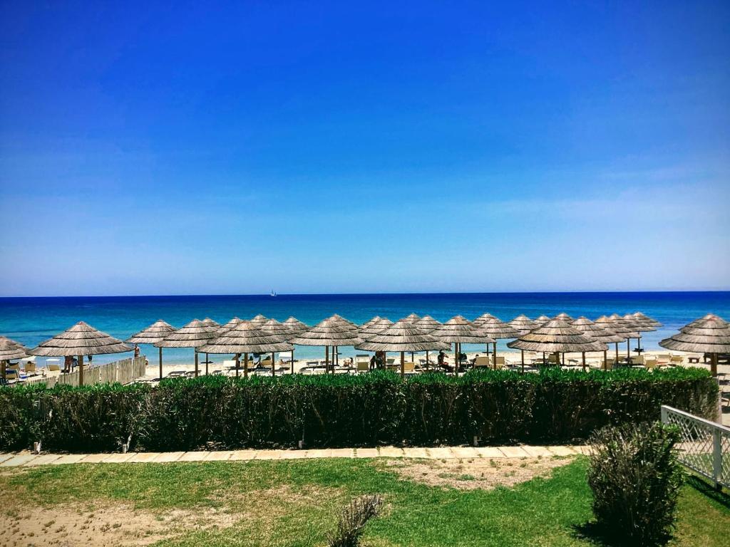 een groep parasols op een strand met de oceaan bij Casamemi San Lorenzo a due passi dalla Spiaggia in Reitani