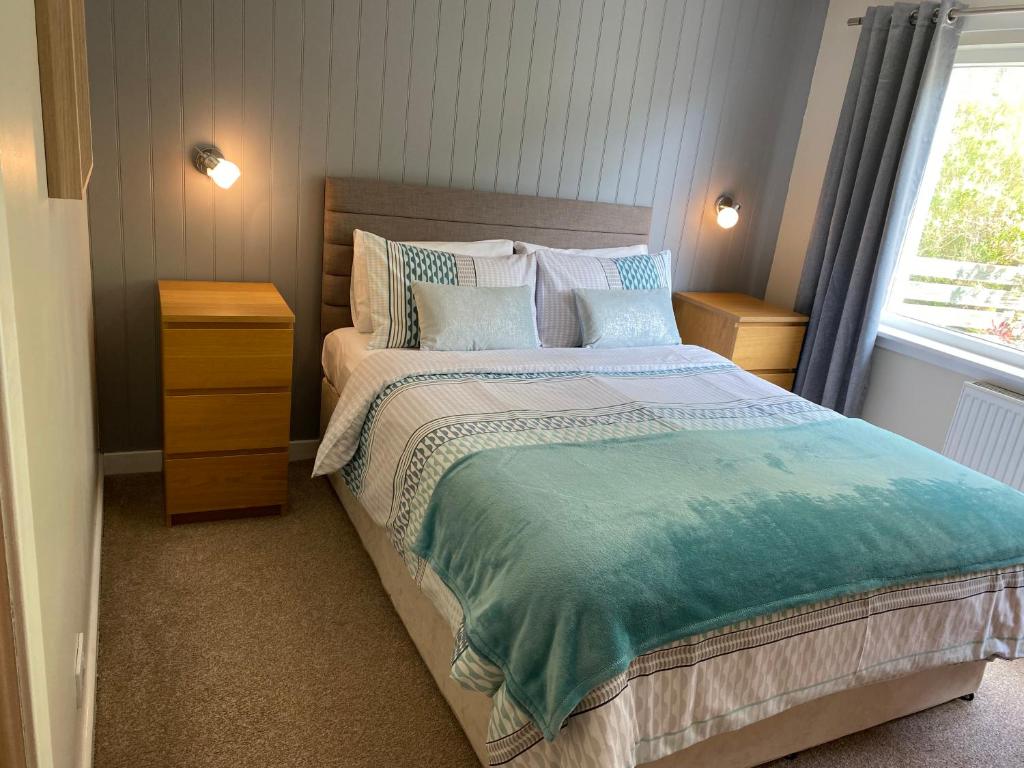 a bedroom with a bed with blue and white sheets and a window at Edgemont Annexe Oban in Oban