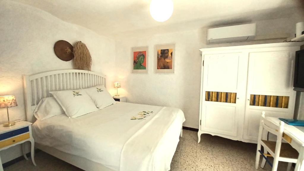 a bedroom with a white bed and a white cabinet at La cigale in Gourdon