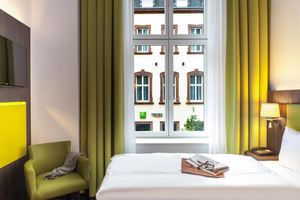 a hotel room with a bed and a window at Ibis Styles Trier City in Trier