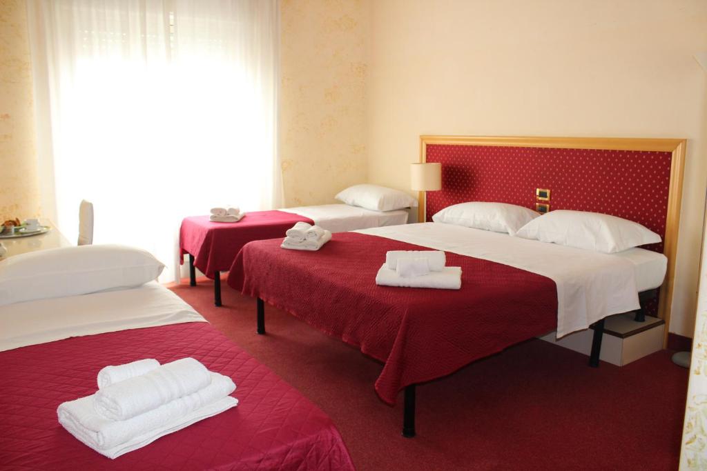 una camera d'albergo con due letti con lenzuola rosse di Hotel Palace Masoanri's a Reggio di Calabria