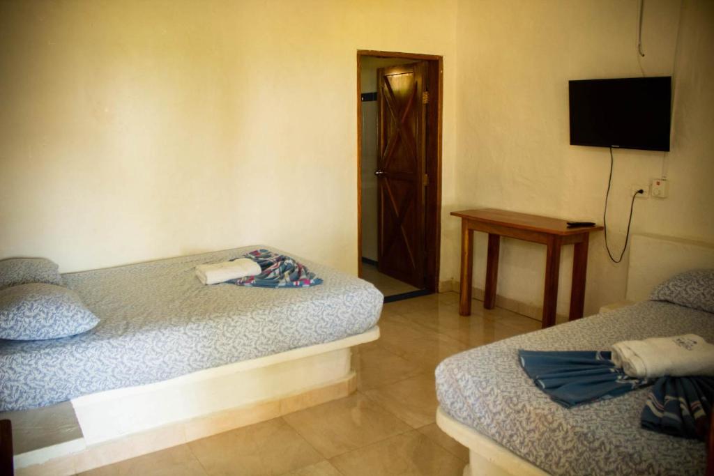 Habitación con 2 camas, TV y mesa. en Finca Hotel La Manuela, en Arboletes