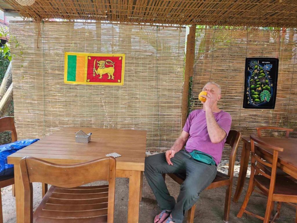 Een man die aan een tafel zit te praten met een mobiele telefoon. bij Mallika City Villa in Negombo