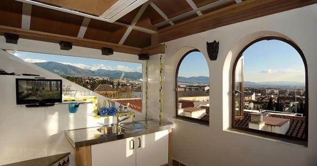 a kitchen with two windows and a view of a city at Golondrinas de la Alhambra in Granada