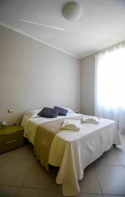 a white bedroom with a large bed with blue pillows at CasaA in La Spezia