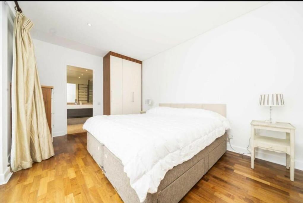 a white bedroom with a large bed and a table at Convenient 2 BDR 2BA Flat in Central London in London