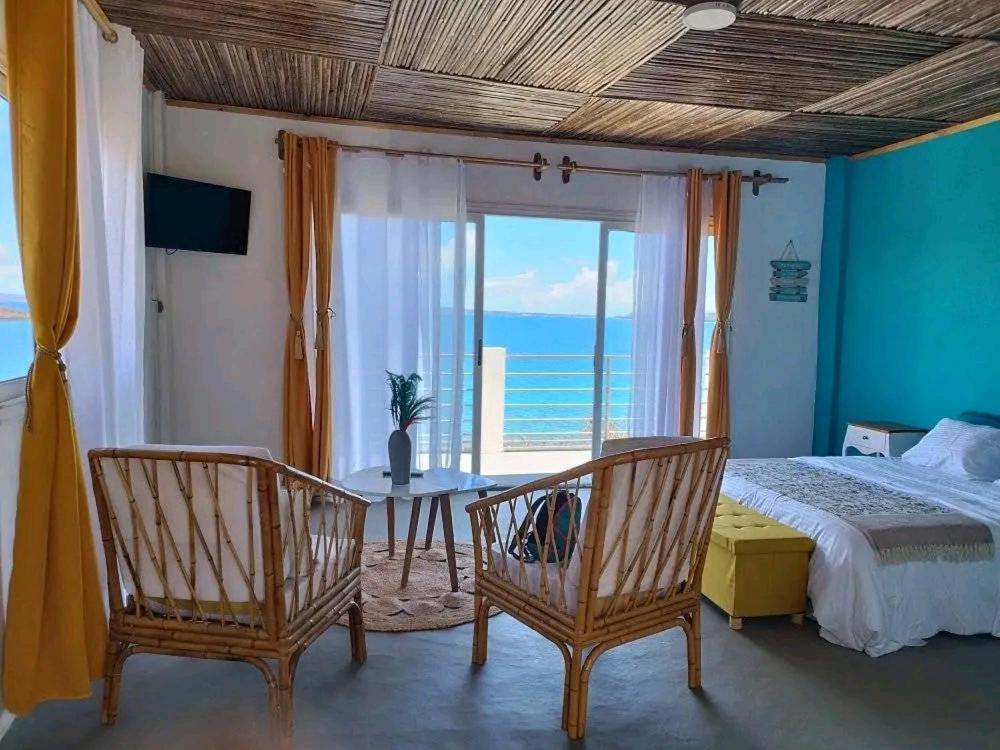 a bedroom with a bed and a table and chairs at Hôtel RIZIKY in Diego Suarez