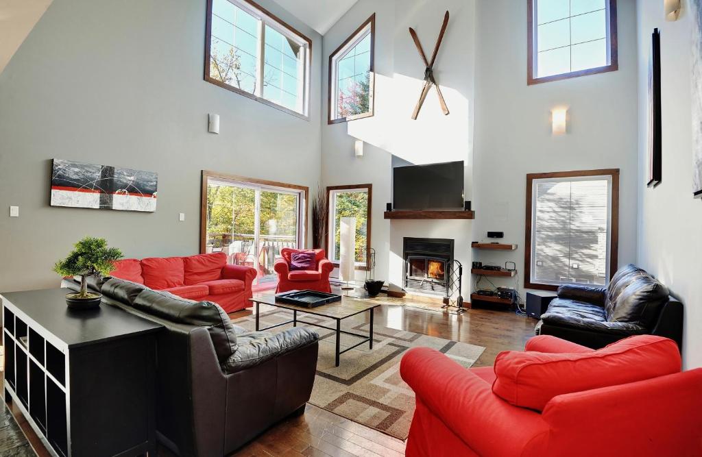 una gran sala de estar con muebles y ventanas de color rojo. en Chalets Alpins-43 Chemin des Skieurs, en Stoneham