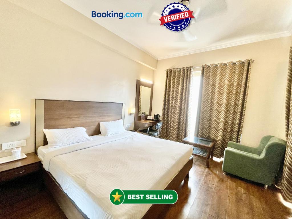 バラナシにあるHOTEL JANHVEE INN ! VARANASI - Forɘigner's Choice ! fully Air-Conditioned hotel with Parking availability, near Kashi Vishwanath Temple, and Ganga ghatのベッドと緑の椅子が備わるホテルルームです。