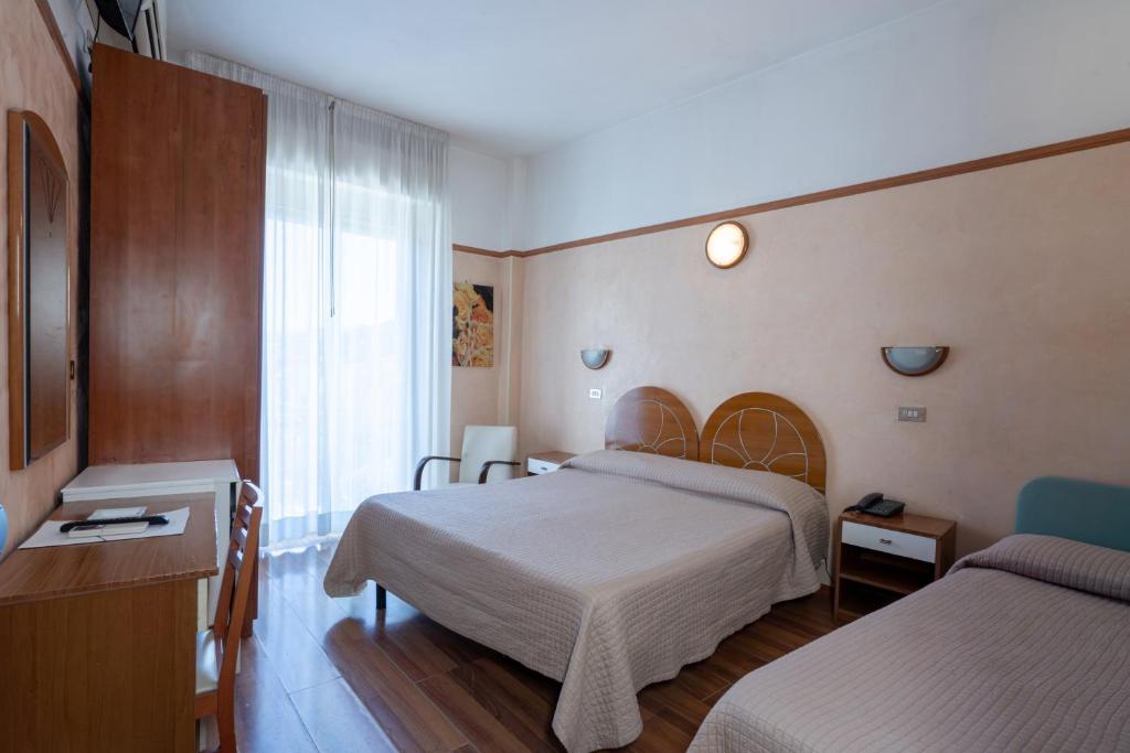 a hotel room with two beds and a window at Hotel Britannia Rimini Marina centro in Rimini