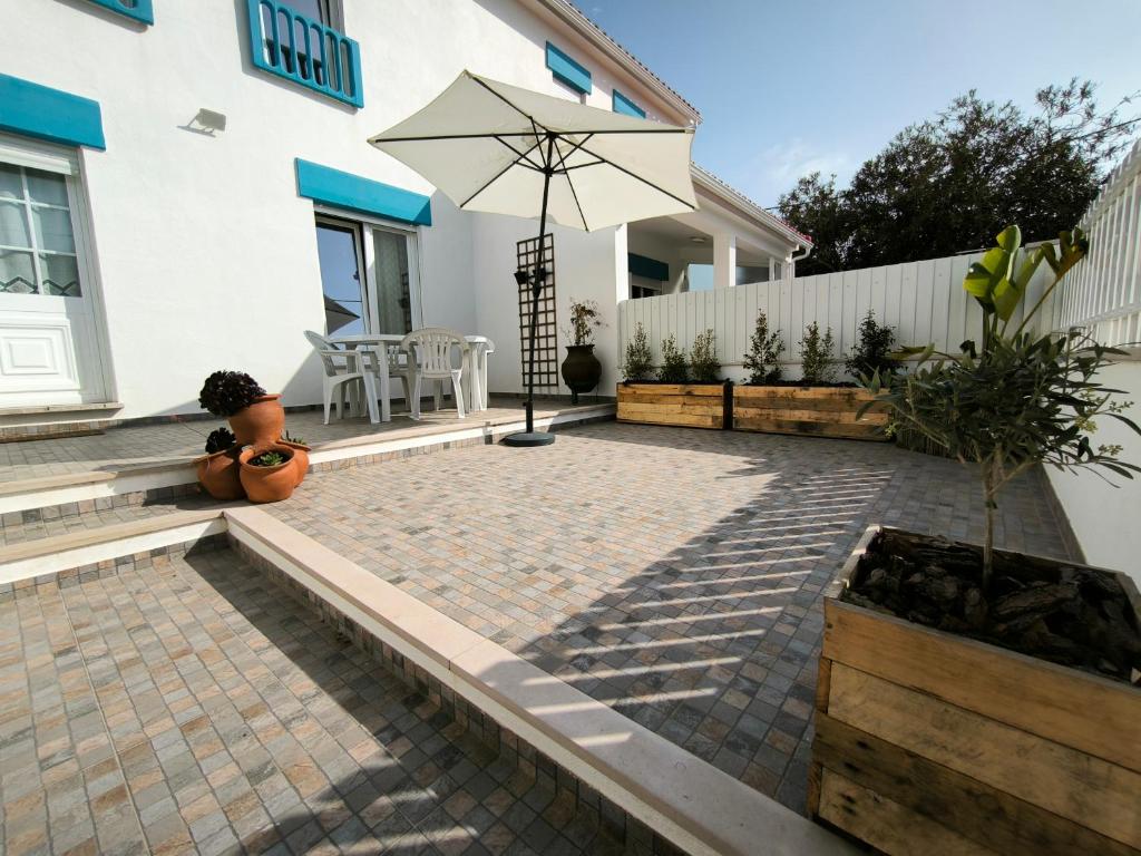 a patio with a table and an umbrella at Casa Alto da Serra Sesimbra in Sesimbra